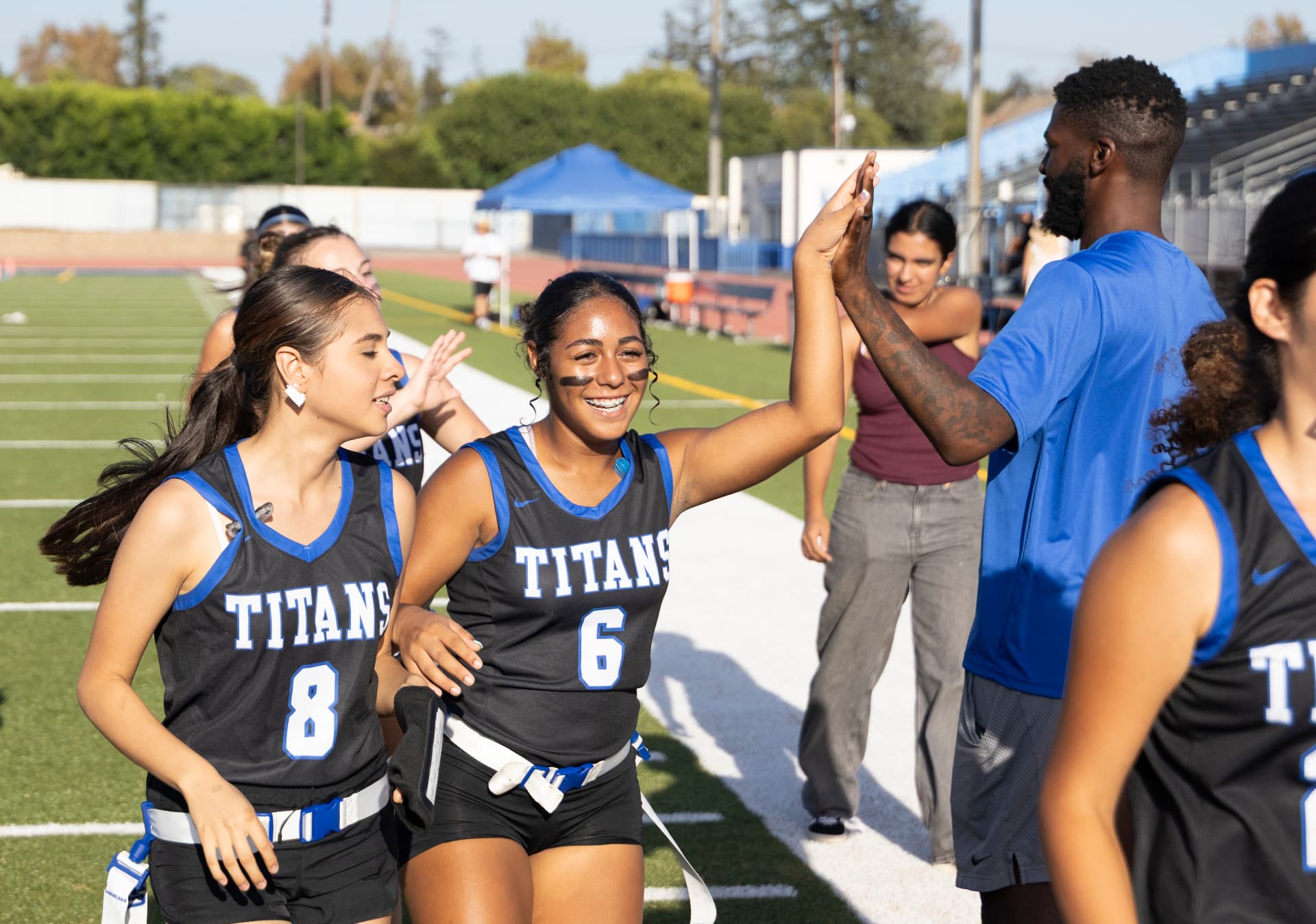 Titans No. 8 and No. 6 high-five a coach on the sideline after a score.