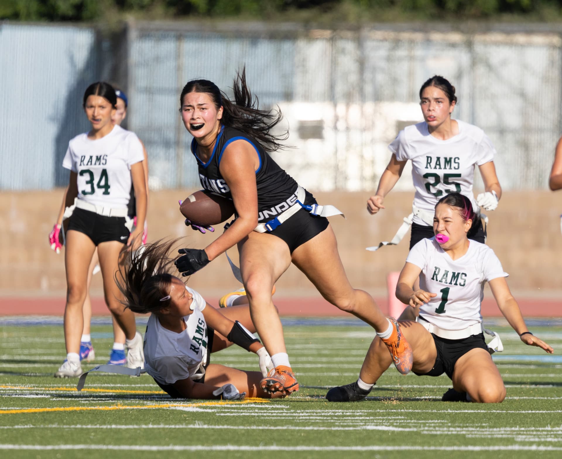 Close view of a Titans ball carrier sprinting past two fallen defenders at the sideline.