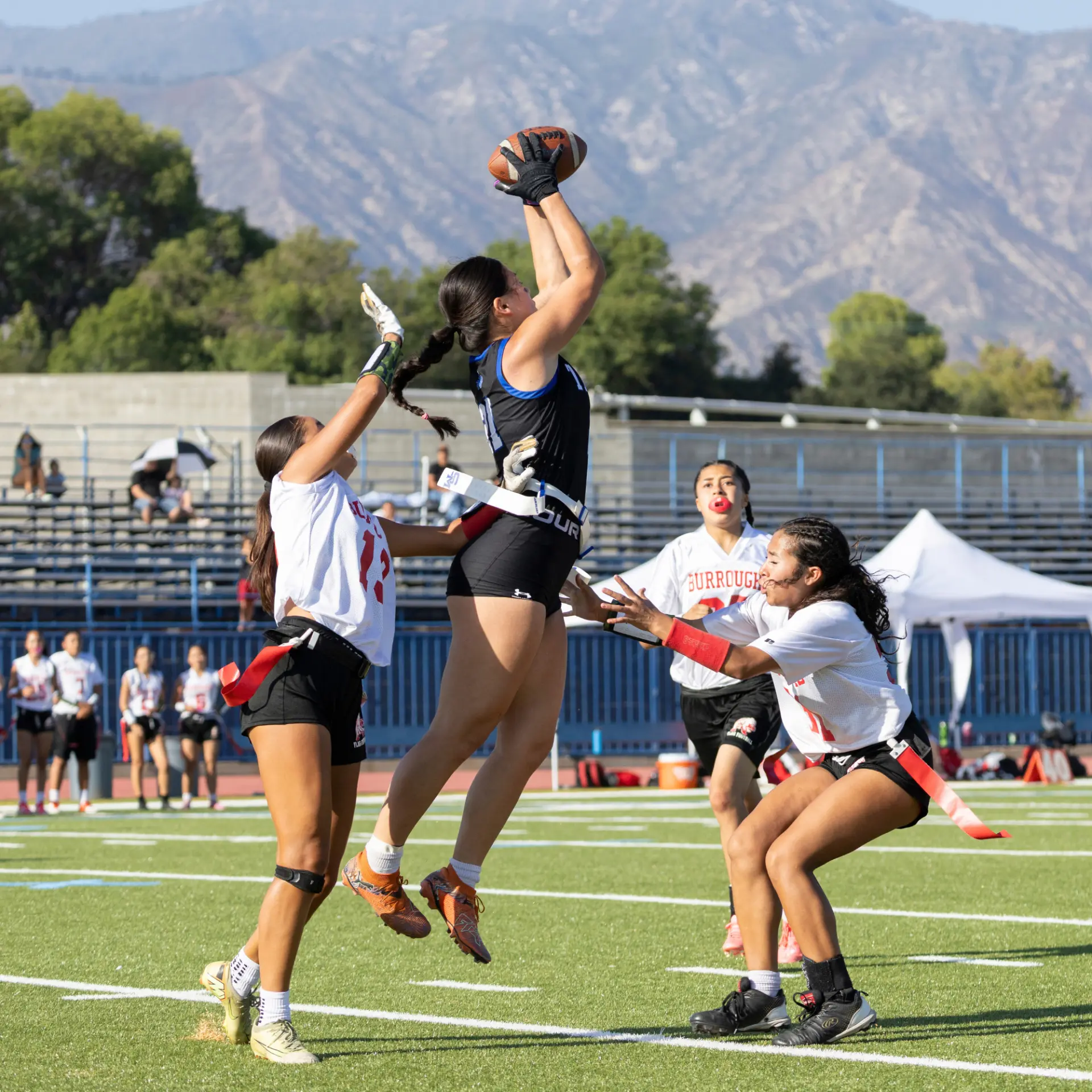Player of the Game Keilani Kooper — a Titans receiver goes up for a catch with Burroughs defenders around her.