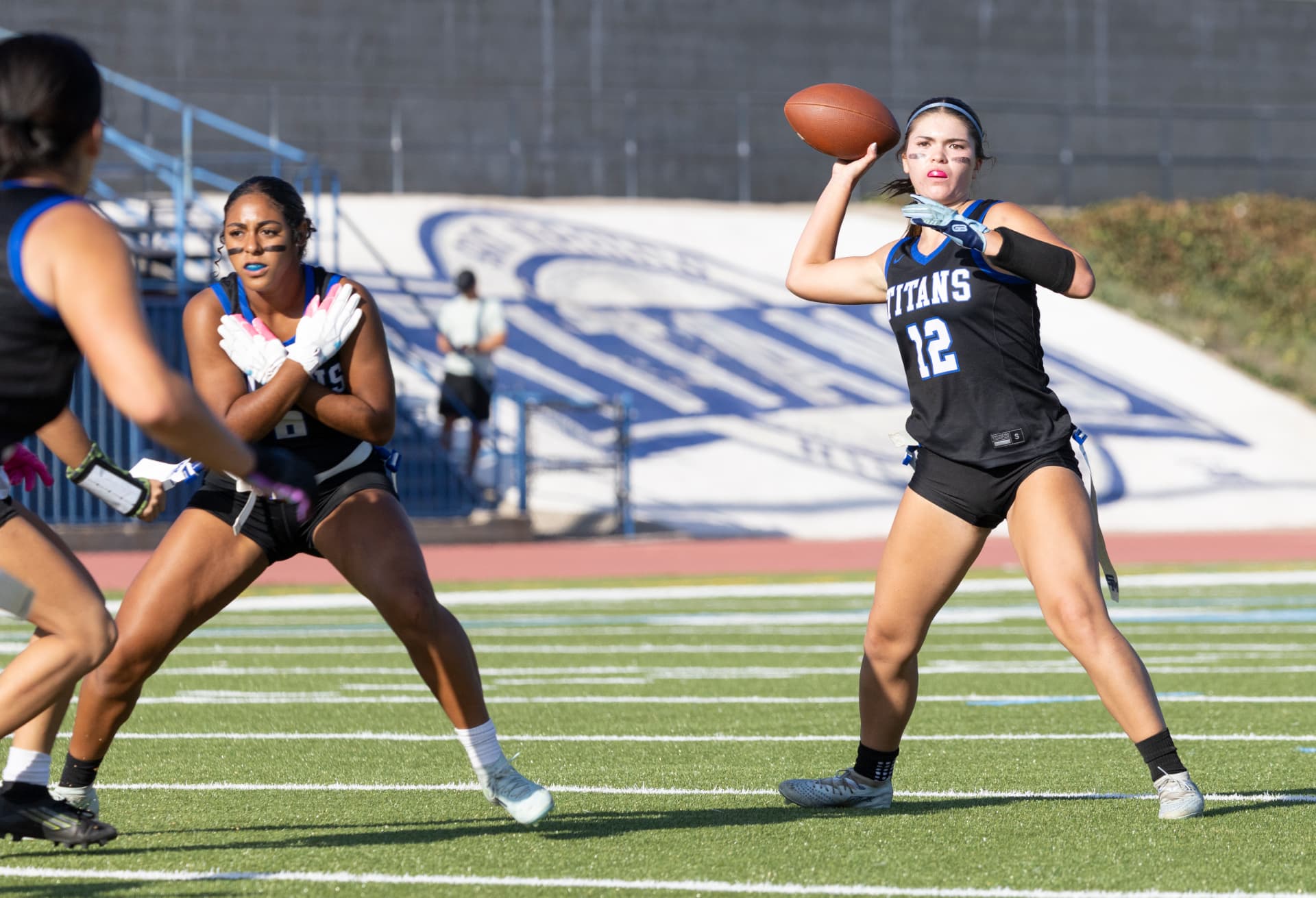 Titans quarterback No. 12 sets up to throw with teammate No. 6 running her route.