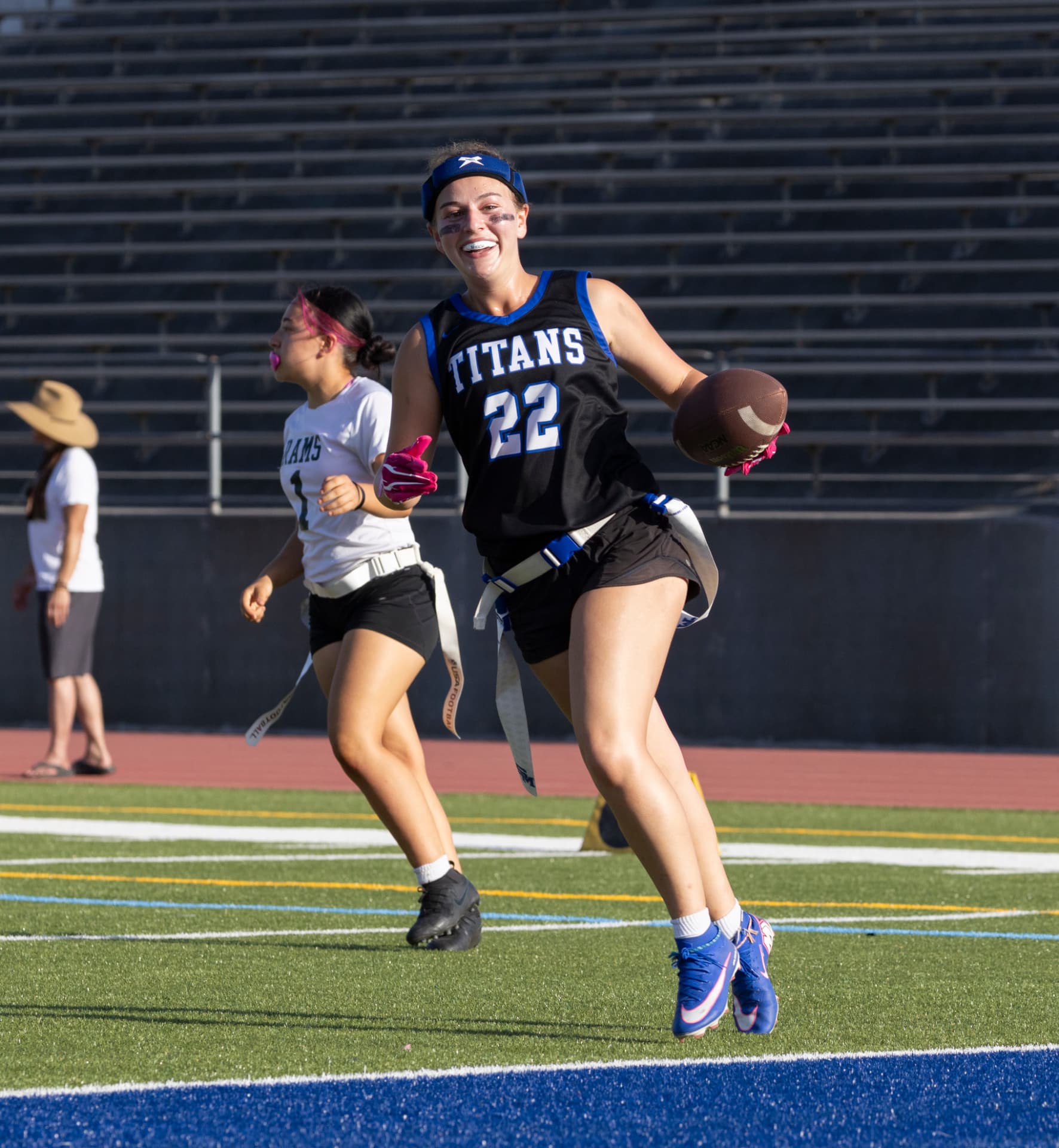 Captain Sloane Maling (No. 22) carries the football downfield with a defender in white in pursuit.