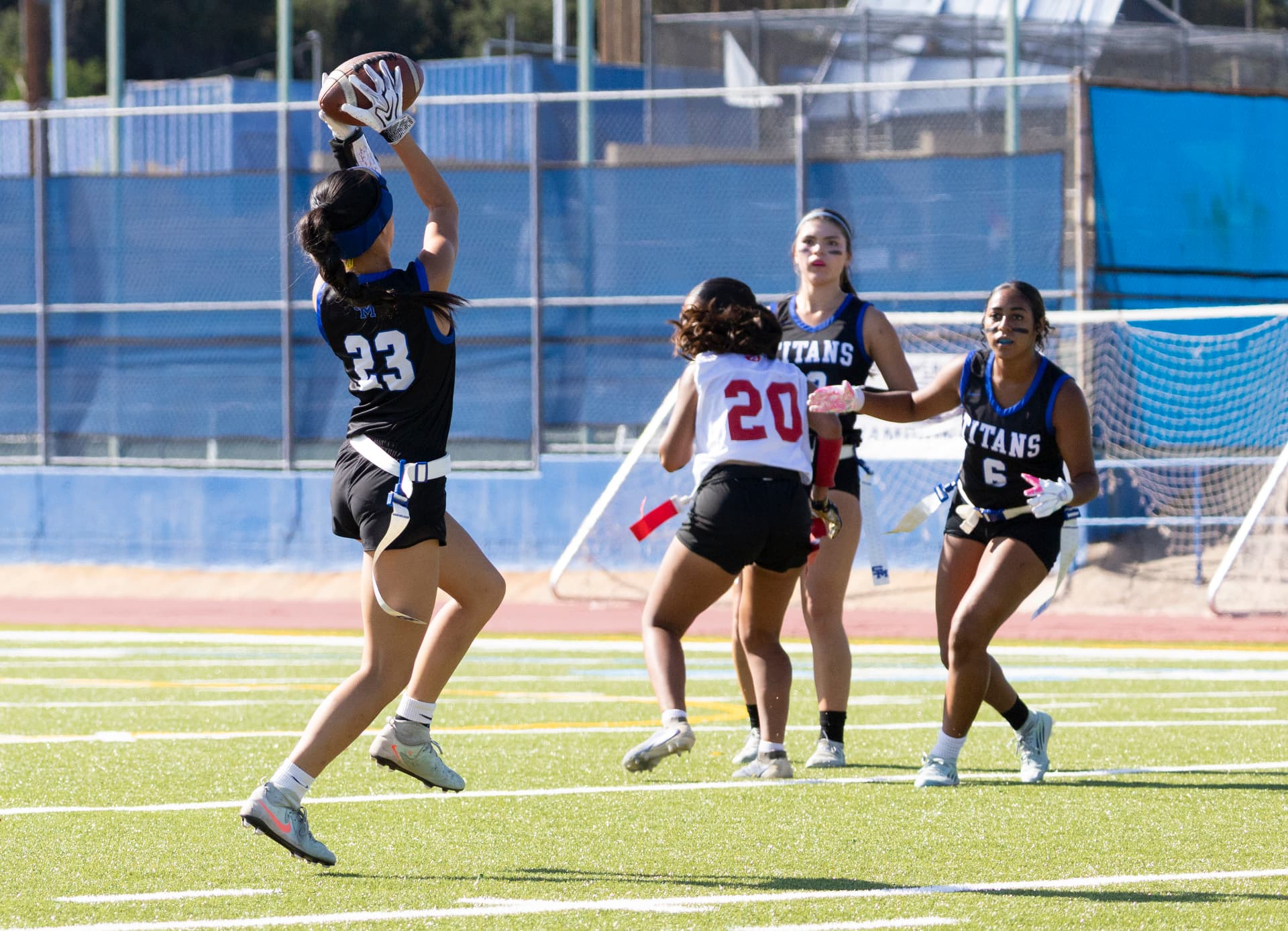 Titans No. 23 leaps to pull down a catch over a defender in white during a home game.